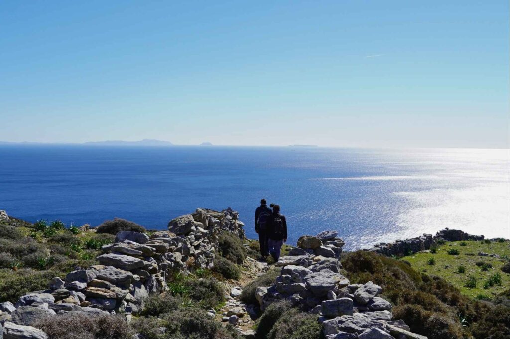 Ancient Stone Kalderimi in Amorgos Hikers descending an ancient stone kalderimi overlooking the deep Aegean Sea in Amorgos - Hike Greece